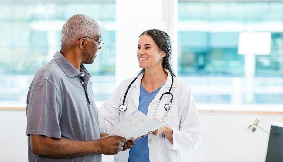 The mid adult female doctor and her senior adult male patient discuss the home healthcare options listed in the brochure.